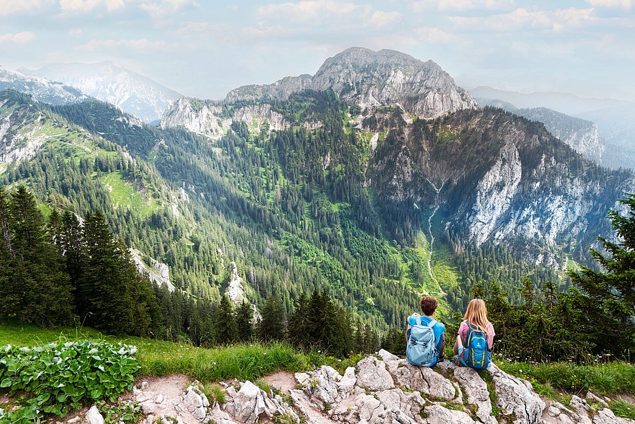 Zwei Wanderer sitzen am Wegesrand und schauen in die Bergwelt Zwei Wanderer sitzen am Wegesrand und schauen in die Bergwelt