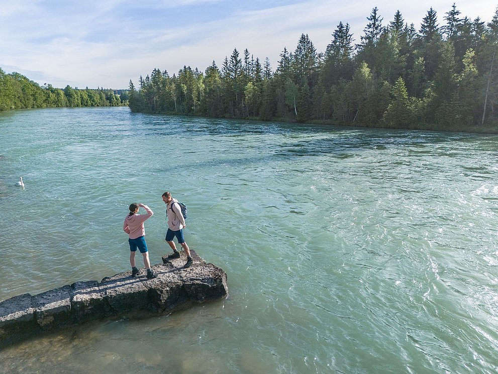 Zwei Personen auf Steinen am Flußufer Zwei Personen auf Steinen am Flußufer